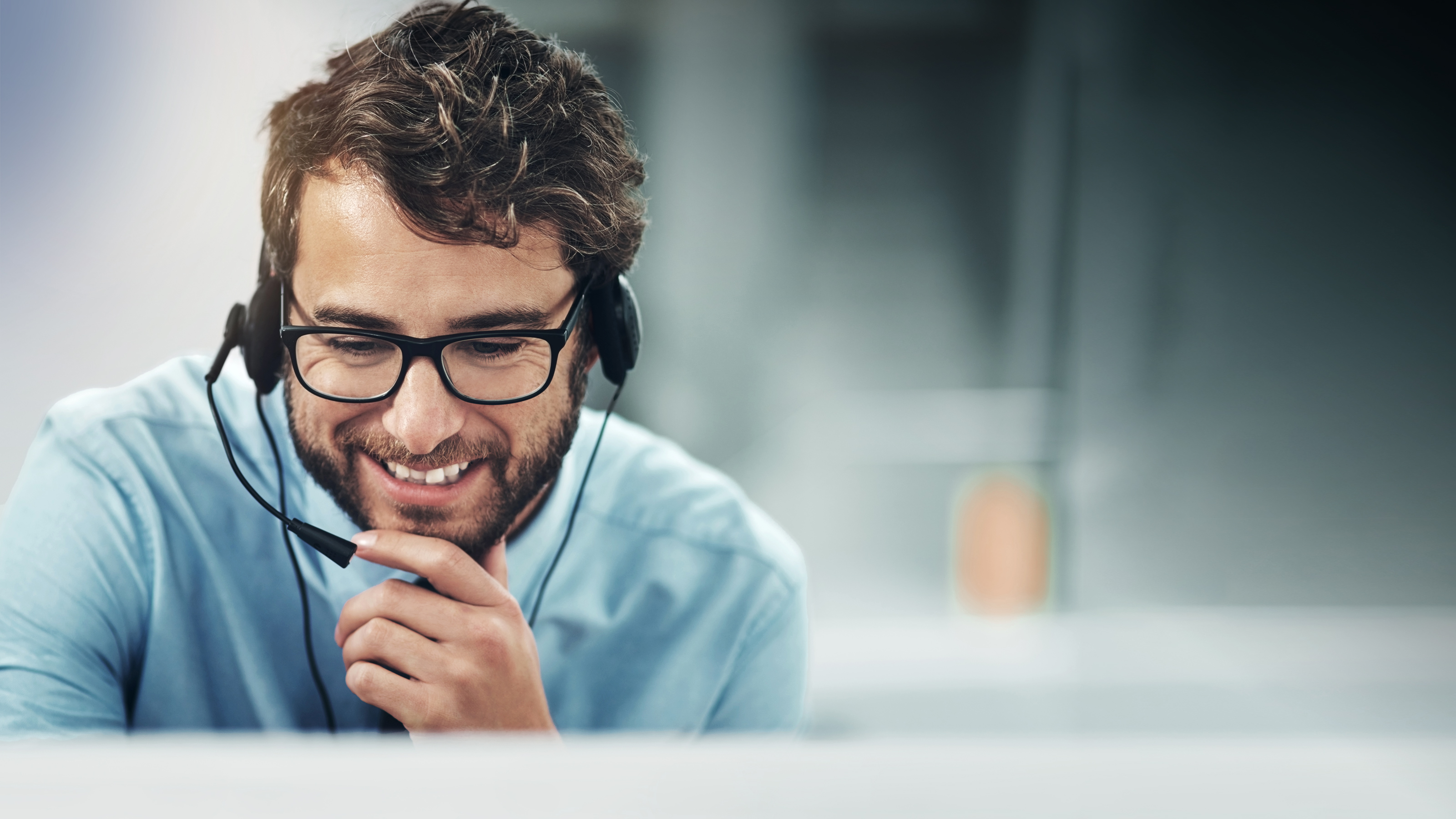 Branchen Call Center Mann mit Brille und Headset lächelt beim Telefonieren